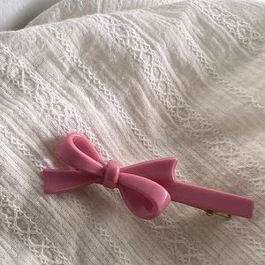 Gros plan d'une pince à cheveux nœud rose doux avec finition brillante sur dentelle