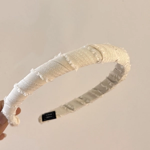 Detail of off-white sponge headband with frayed edges and handmade fabric label