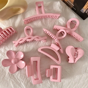 Various pink hair claw clips in floral and geometric shapes on a white paper background