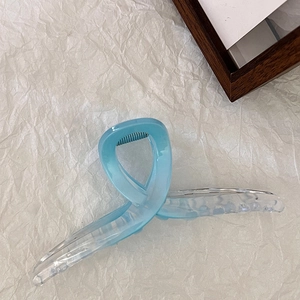 Dettaglio della pinza per capelli azzurra traslucida con design a torsione e molla metallica