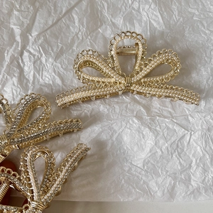 Elegante goldene Haarklammern mit Schleife, Perlen und Strass auf weißem Papier