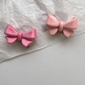 Détail de barrettes à cheveux nœud rose avec attaches en métal doré sur papier texturé