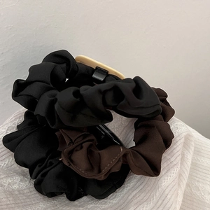 Detail of vintage matte fabric hair scrunchies in black and dark brown with soft pleats