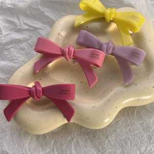 Détail de quatre barrettes à cheveux nœuds en résine colorée sur un plateau de présentation