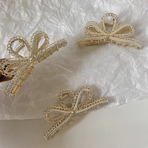 Detail von drei goldenen Haarklammern mit Perlen und Strass auf weißem Papier