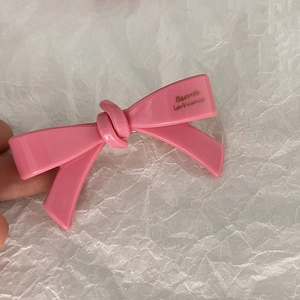 Détail d'une pince à cheveux rose à double nœud brillant avec décor doré