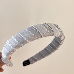 Close-up of lilac fabric headband featuring spiral twisted design and frayed fringe details
