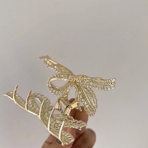 Eleganter goldener Haarklammer aus Metall mit Schleife aus Spitze in der Hand