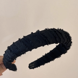 Detail of handmade padded black headband with frayed edge texture and fabric label