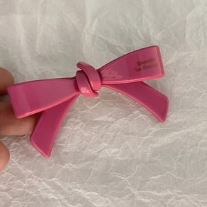 Gros plan sur une barrette nœud rose brillant avec détails en lettres dorées