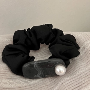 Detail of black fabric hair scrunchie with marble resin accent and white pearl bead