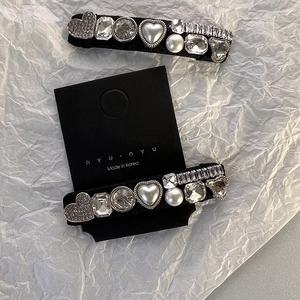Détail de deux barrettes vintage avec cristaux de cœur et perles sur un support noir