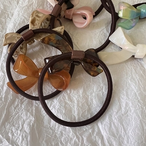 Close-up of assorted French acetate bow hair ties in multiple colors on white paper