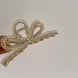 Detail einer Haarklammer-Schleife aus Goldlegierung mit weißen Perlen und Strass