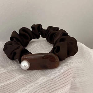 Detail of coffee brown satin scrunchie with marble resin accent and white pearl