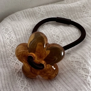 Nahaufnahme des Bernstein-Resin-Blumen-Haargummis mit Marmortextur auf weißer Spitze