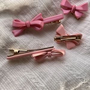 Lot de barrettes à cheveux nœud rose avec pinces crocodiles dorées sur fond blanc