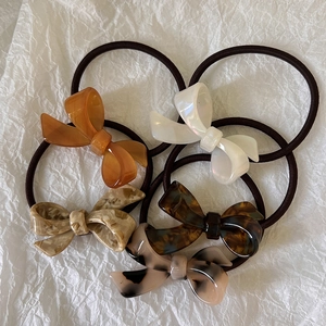 Detail of five acetate bow hair ties in assorted tortoiseshell and marble patterns