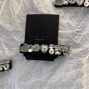 Vue détaillée des ornements en strass de cœur et perles sur une barrette noire chic