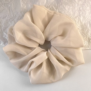 Makroansicht des beigen Oversize-Haargummis aus Chiffon mit weichen Stofffalten