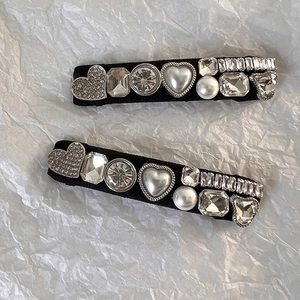 Gros plan de barrettes noires avec strass en cœur et perles élégantes sur papier blanc