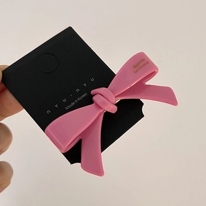 Gros plan d'une barrette à cheveux rose brillant en forme de nœud sur carte noire