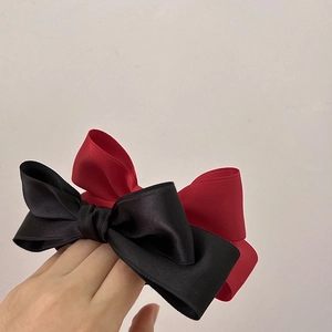 Detailed view of handmade black and burgundy satin bow hair ties with smooth silk texture