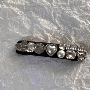 Détail macro d'une pince à cheveux française avec strass en cœur et perles élégantes