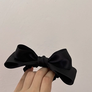 Detailed view of elegant black satin double bow hair tie with high elastic band texture
