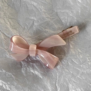 Dettaglio del fermaglio a fiocco rosa in acetato con elegante texture marmorizzata