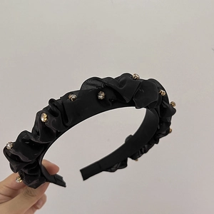 Dettaglio del cerchietto nero plissettato con strass scintillanti su tessuto chiffon