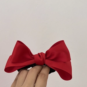Detail of red satin double-layer bow hair tie with a soft glossy texture and elastic band