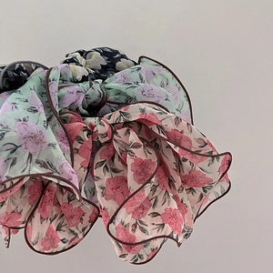 Detailed macro view of chiffon floral scrunchies with delicate layered pleats and dark edging