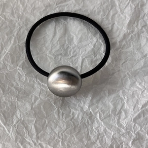 Detailed view of silver brushed metal heart ball on a black high elasticity hair tie