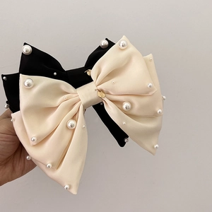 Détail des barrettes nœuds en satin avec perles blanches et pendentif doré fait main