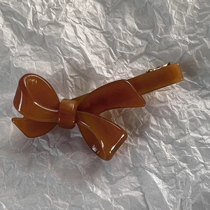 Dettaglio di un fermaglio per capelli a fiocco in acetato ambra con texture tartaruga