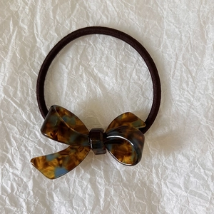 Detail of tortoiseshell pattern acetate bow on high-elasticity brown hair scrunchie