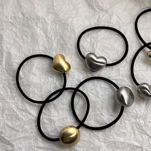 Detail of vintage brushed metal heart and bead charms on elastic hair ties in gold and silver