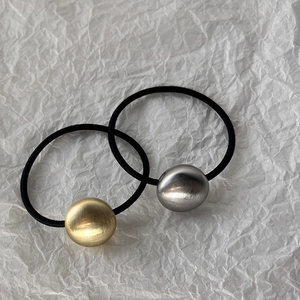 Close-up of brushed gold and silver heart-shaped metal charms on elastic hair ties