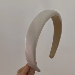 Detail of the thick padded ivory headband showing the glossy fabric texture and lining