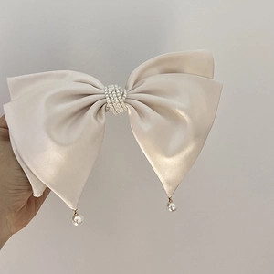 Detail of elegant cream satin bow hair clip with luxury pearl cluster and hanging beads