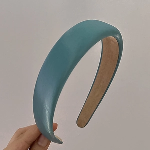 Close-up of a teal blue padded headband showing soft fabric texture and brown non-slip lining
