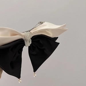 Detailed side view of elegant satin bow hair clip with luxury pearl beads and pendants