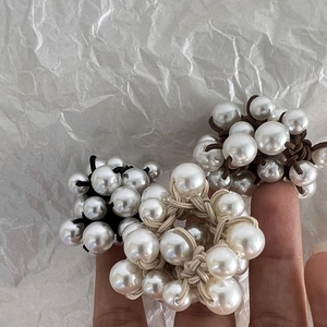 Elegant pearl weave hair ties in black, brown, and beige colors on a clean white background
