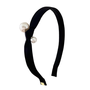 Elegant black satin knotted headband with asymmetrical pearl accents and metal logo charm