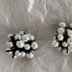 Close-up of elegant pearl hair ties in black and brown colors with large woven pearls