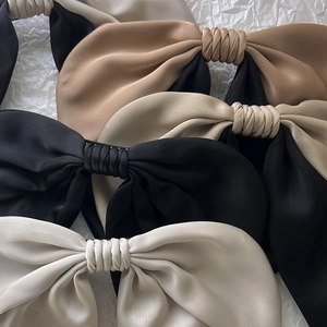 Elegant satin bow hair clips in assorted colors including black, beige, and champagne