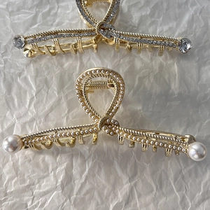 Dettagli di grandi mollette in lega dorata con strass scintillanti e perle eleganti