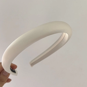Detailed close-up of a thick white padded sponge headband with a satin finish texture