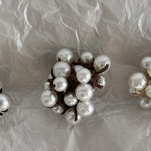 Macro detail of elastic hair tie featuring lustrous white pearls in a cluster arrangement